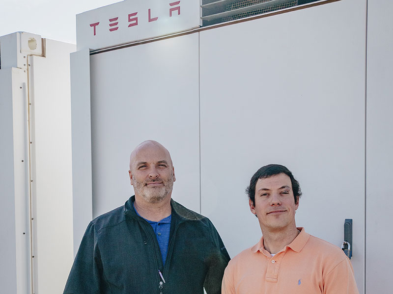 Two men in front of battery pack