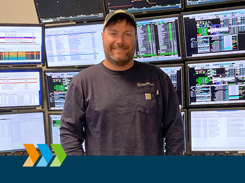 man standing in front of monitors and smiling