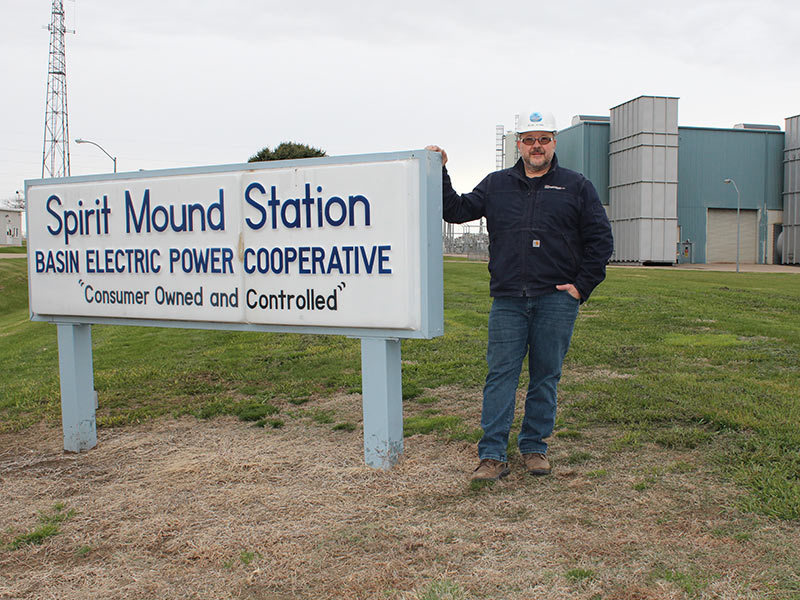 Man standing by sign that says Spirit Mound Station