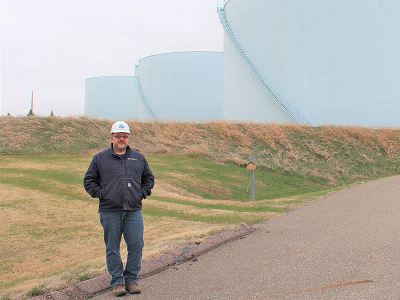 man standing in front of large tanks