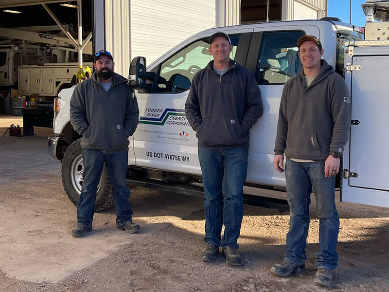 three men standing in front of a pickup