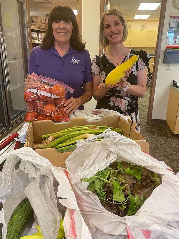 two women smiling and hold vegetables