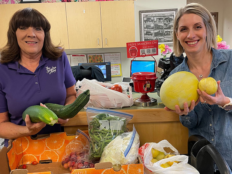 two women smiling and hold vegetables