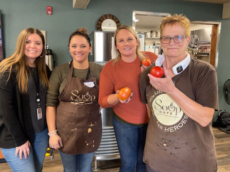 Four women smiling with vegetables