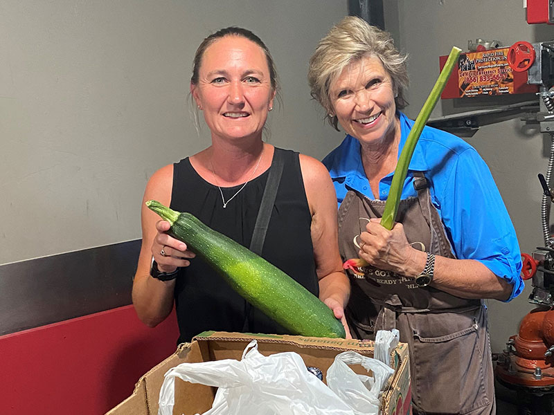 two women smiling and holding vegetables