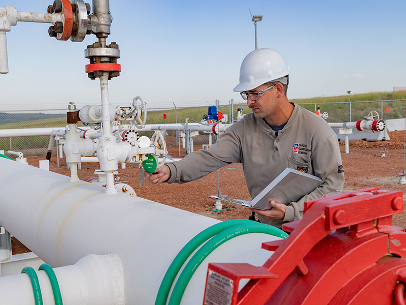 Hunter Eslinger, pipeline engineer III at Dakota Gas, poses for a photo among pipelines at the site near Beulah, North Dakota. Eslinger is Dakota Gas’ sole pipeline engineer.