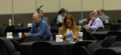 People sitting at multiple tables, each viewing a phone