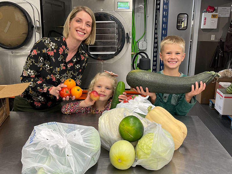 woman and two children with vegetables