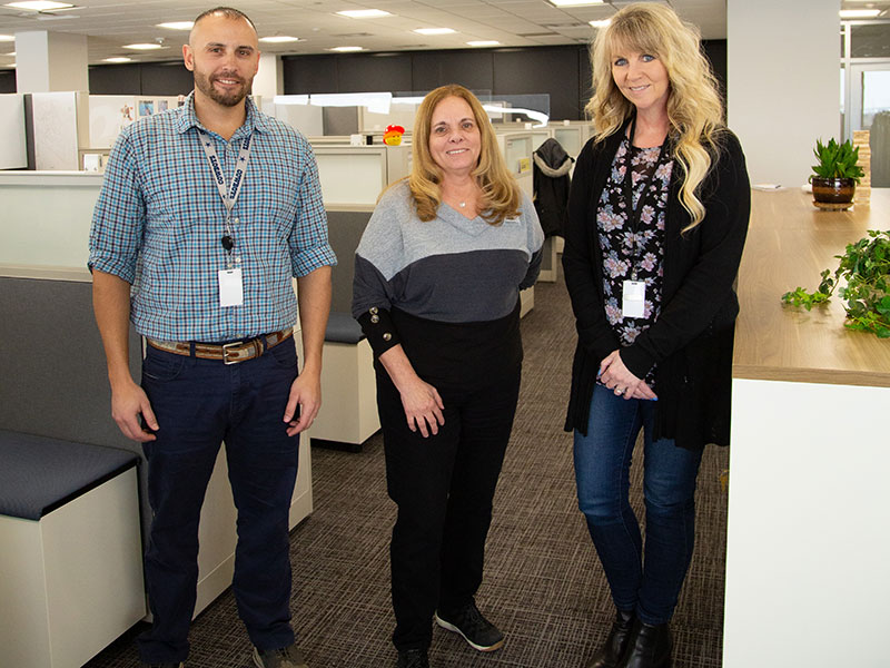 three people standing in an office setting